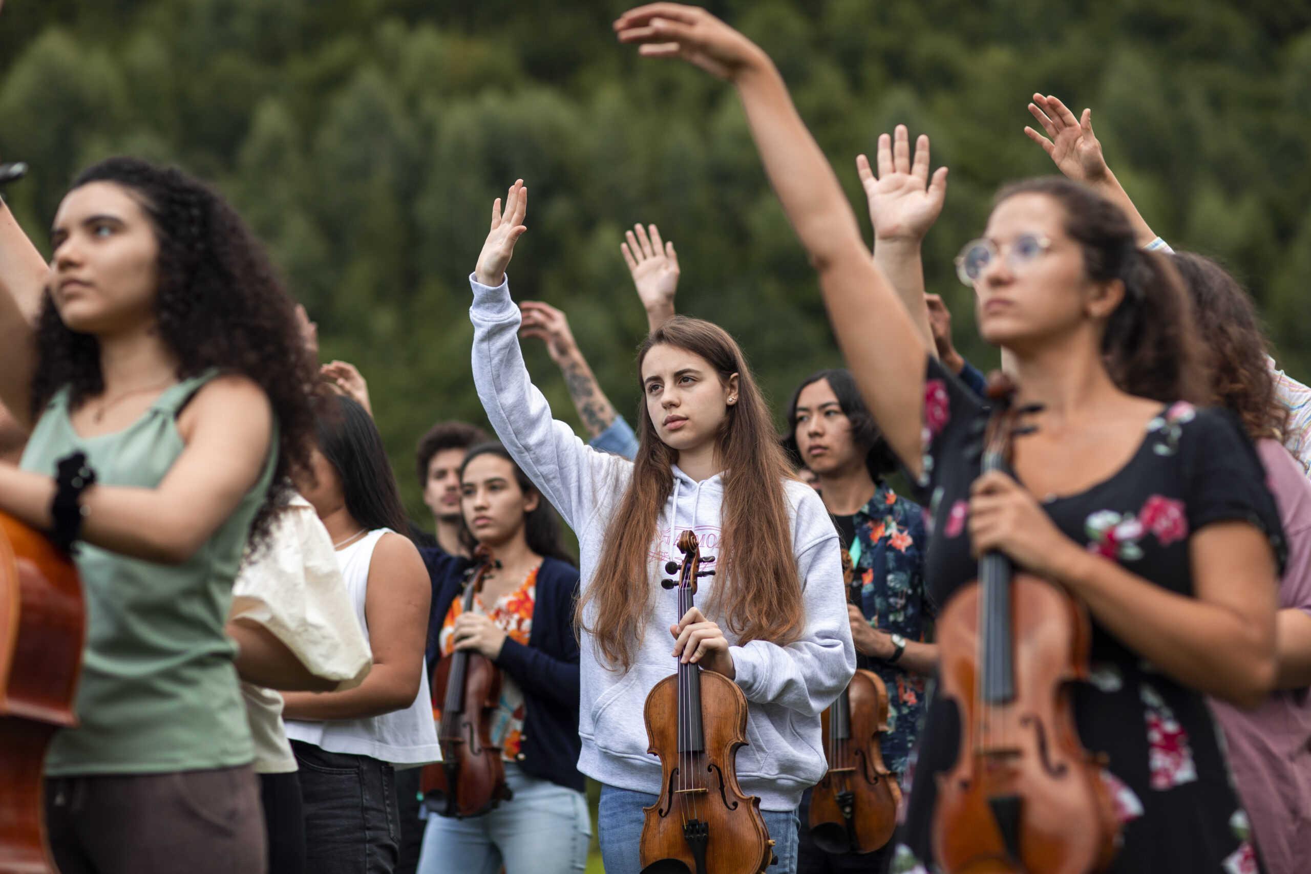 gente con la mano levantada y un violín